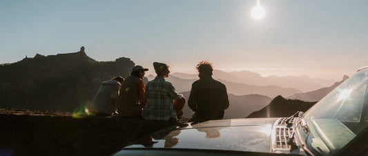 A group sat in low light, looking over a mountain vista