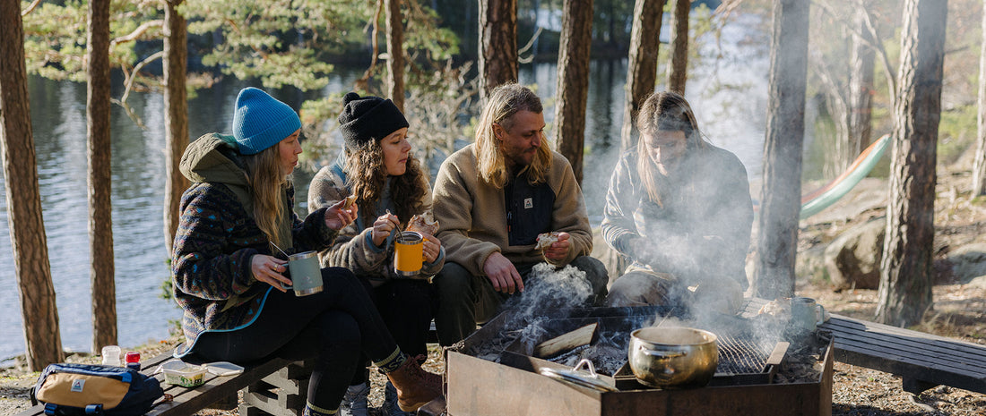 A group sat around a fire, in fleeces